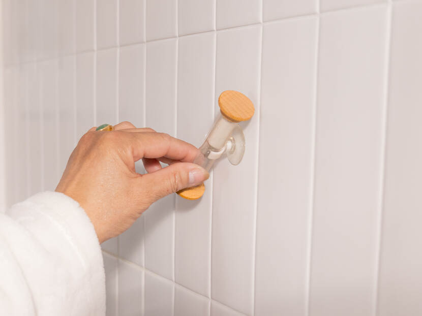 Een hand draait een zandloper-douchetimer om,